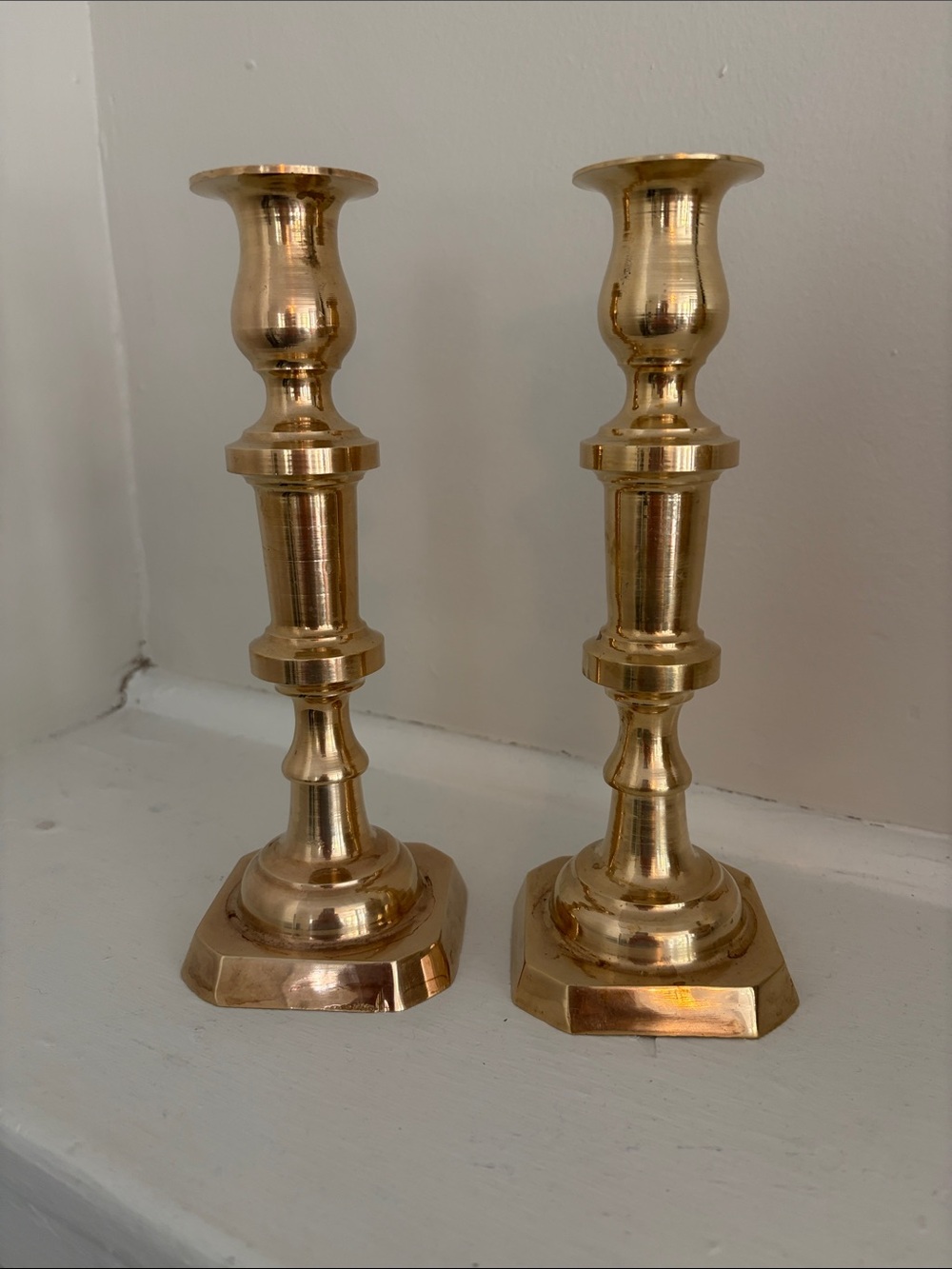 A pair of antique brass candlesticks with hexagonal bases and baluster stems.